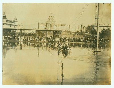 Horizontal Photograph of a Swimmer Crossing a Finish Line. Men in a Boat Watch as Well as Crowds of People on the Shore by Unknown